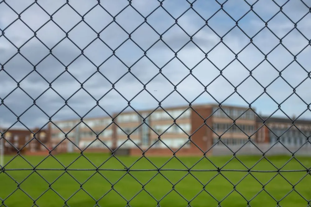 Chainwire perimeter fence running along the edge of a school ground