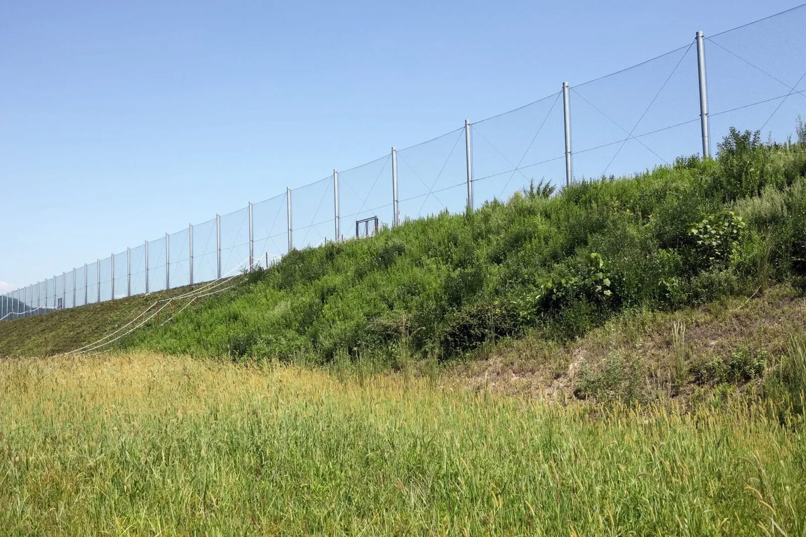 Galvanised chainwire fencing running alongside a rail line